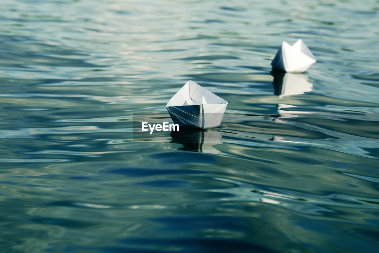 Paper boats made of a sheet of school notebook floating in the water