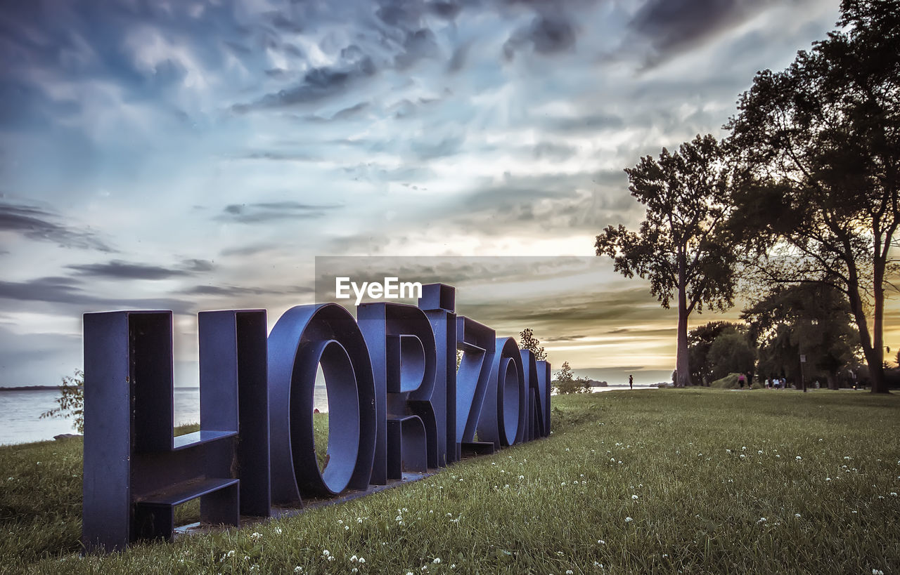 TEXT ON GRASS AGAINST SKY