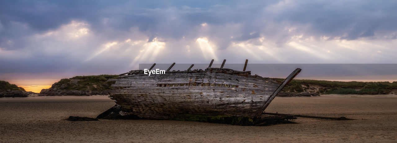 PANORAMIC SHOT OF ABANDONED SHIP ON BEACH DURING SUNSET