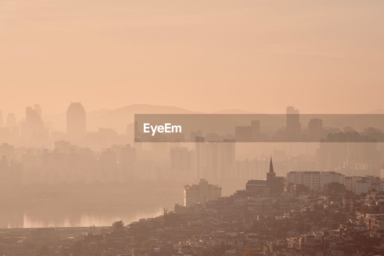 BUILDINGS IN CITY AGAINST SKY AT SUNSET