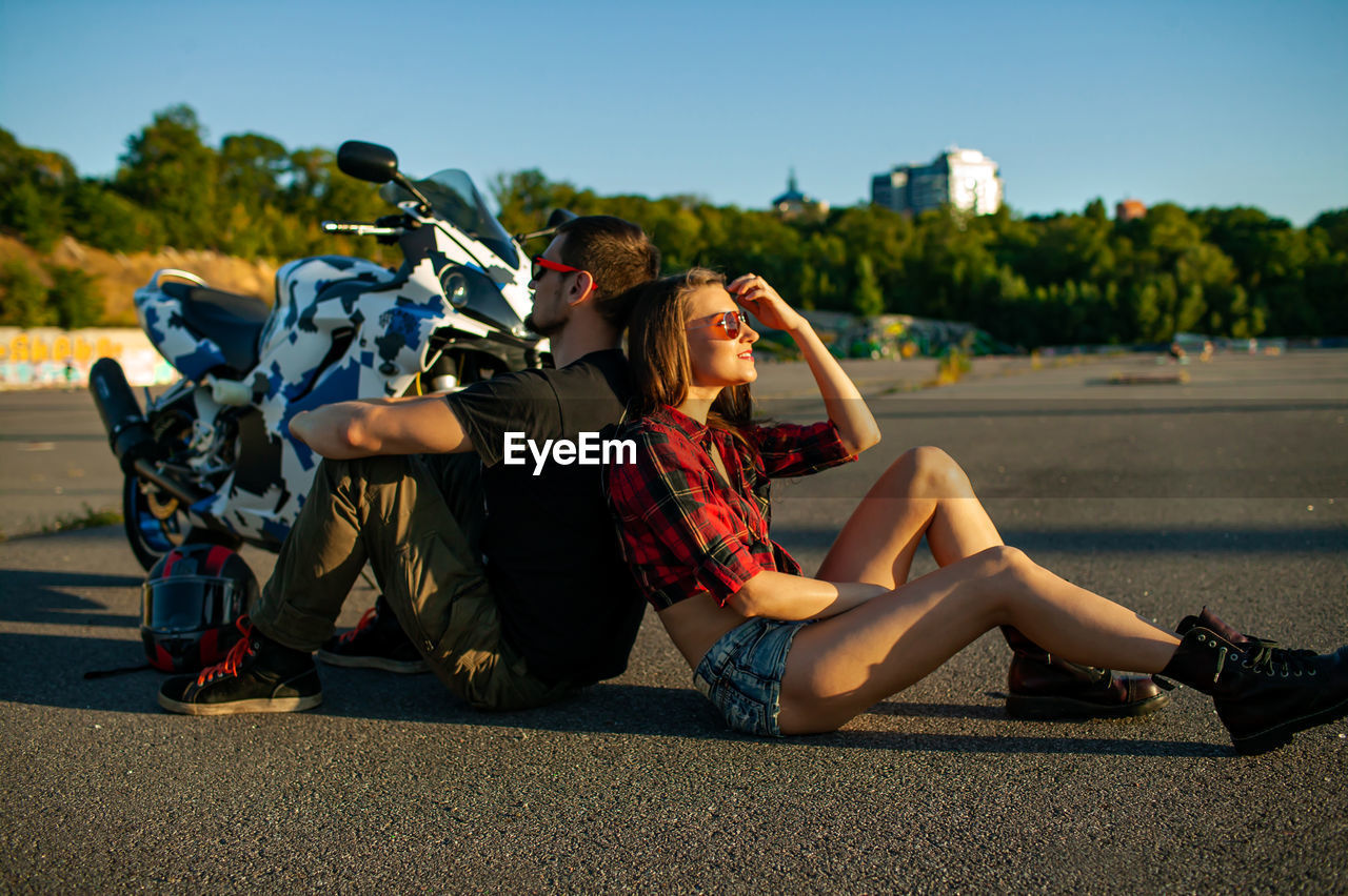 Young couple sitting on road near bike 