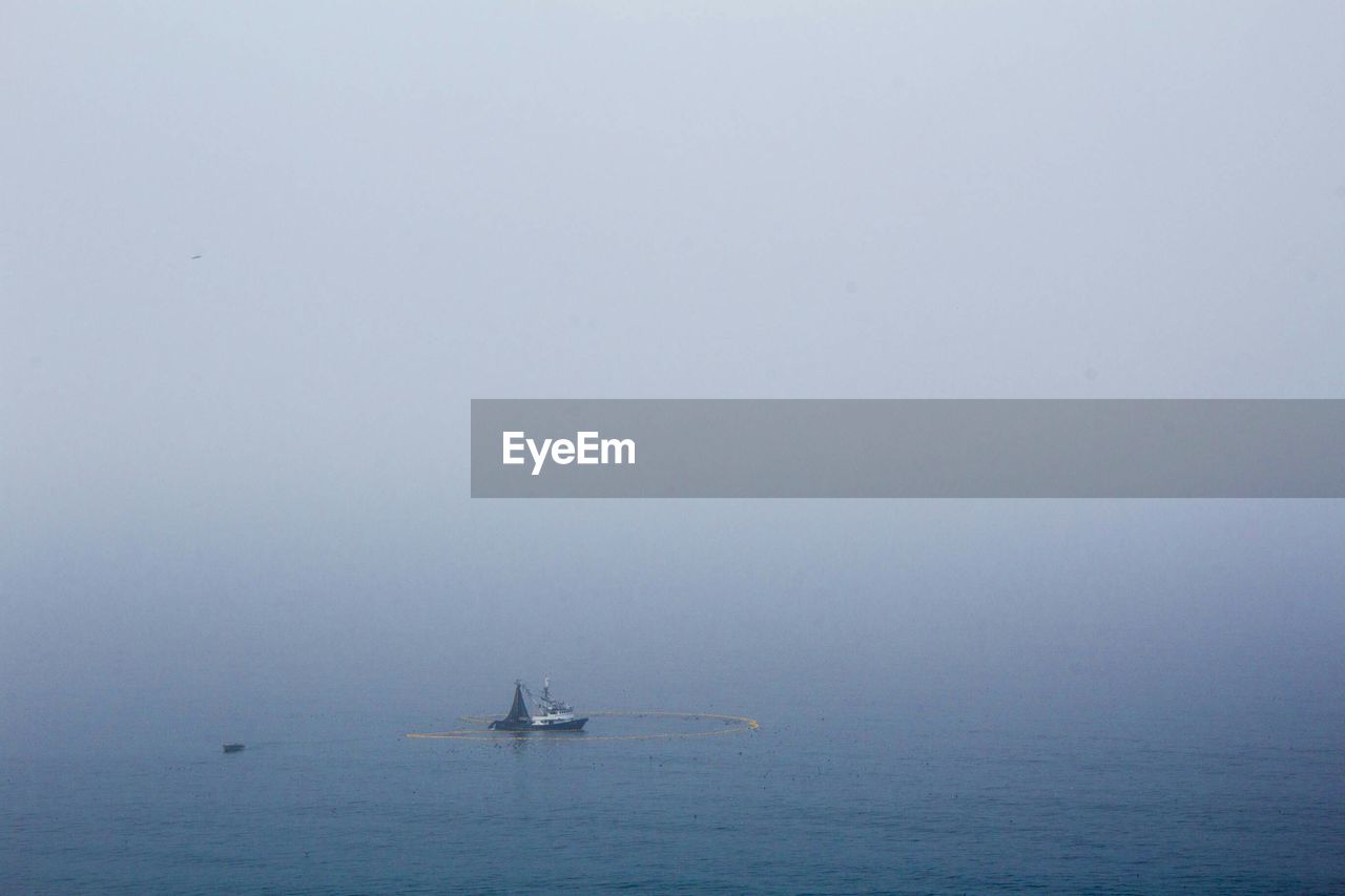 Boat in sea against sky during foggy weather