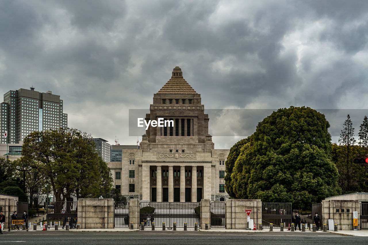 VIEW OF BUILDINGS AND STREET AGAINST CLOUDY SKY