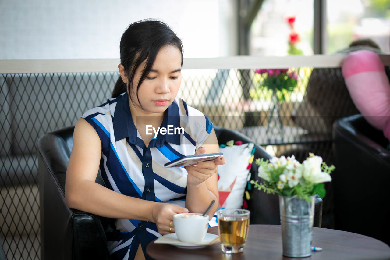 Woman using smart phone while sitting in restaurant