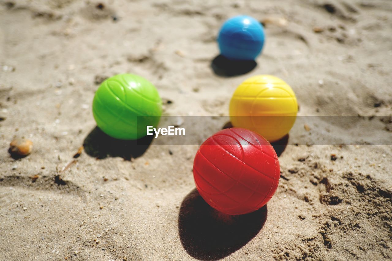 CLOSE-UP OF COLORFUL BALL ON SAND