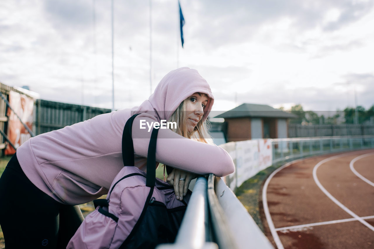 Woman stood by a running track looking thoughtful