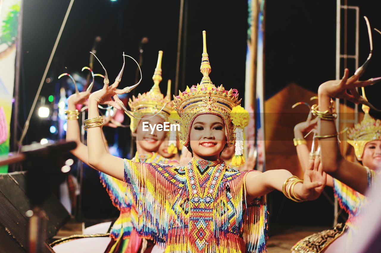 Smiling women in traditional clothing dancing on stage at night