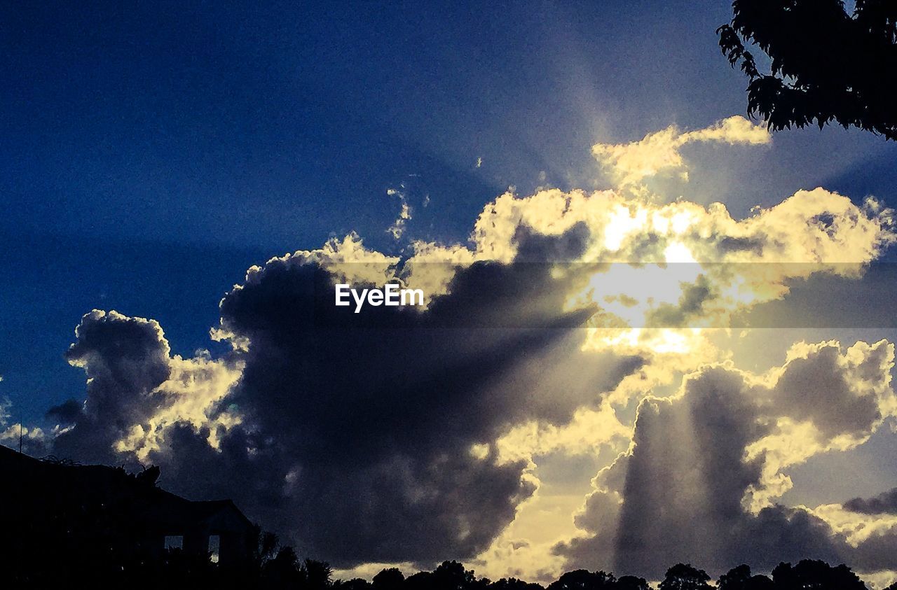 Low angle view of sun shining through clouds