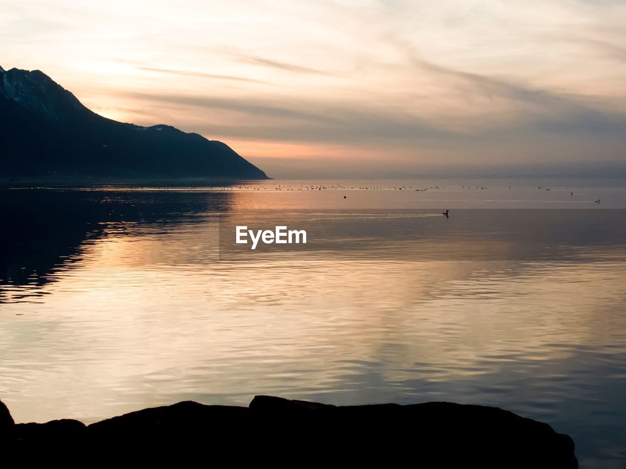 Scenic view of sea against cloudy sky during sunset