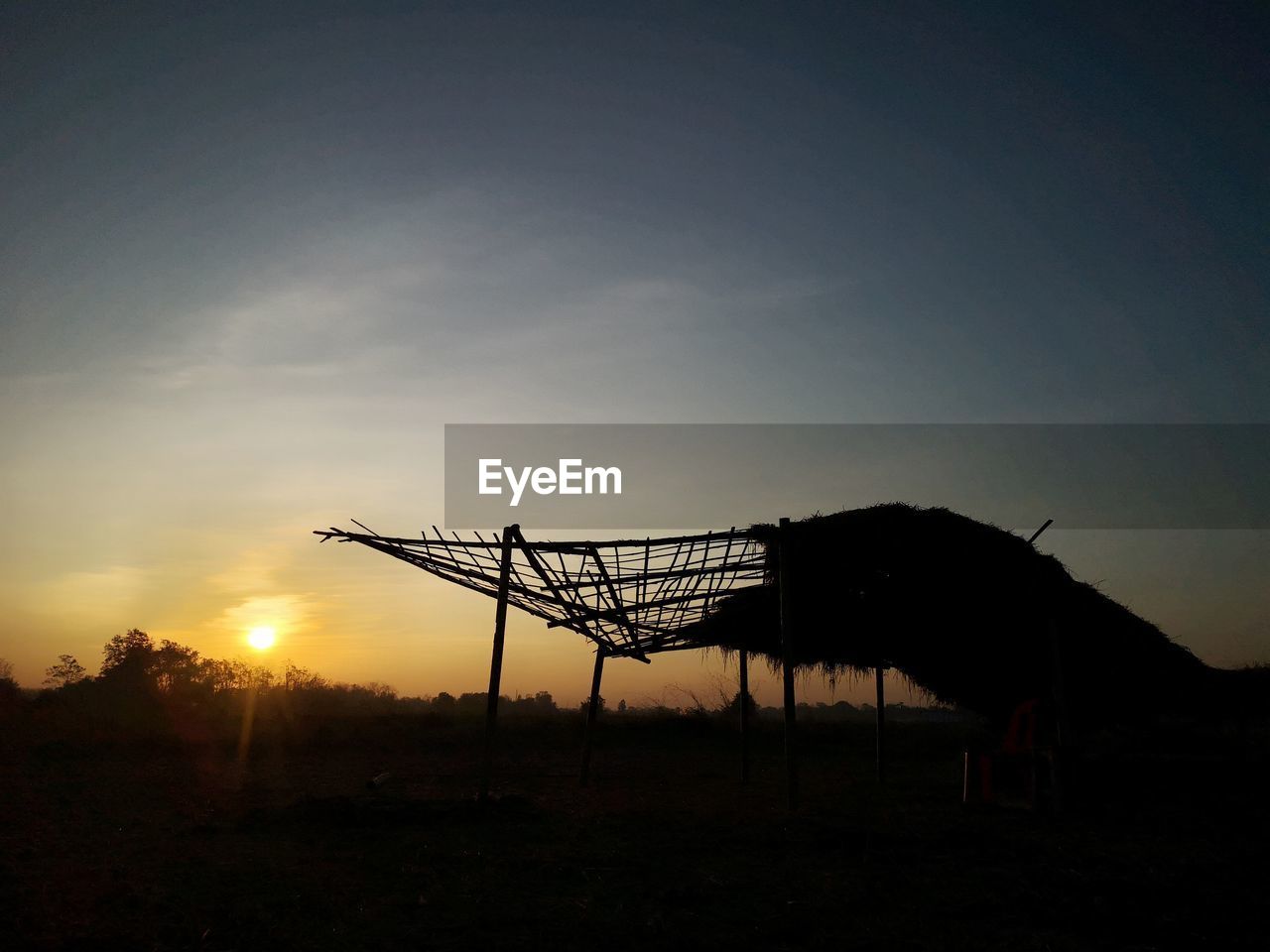 SILHOUETTE CRANE ON FIELD AGAINST SKY DURING SUNSET