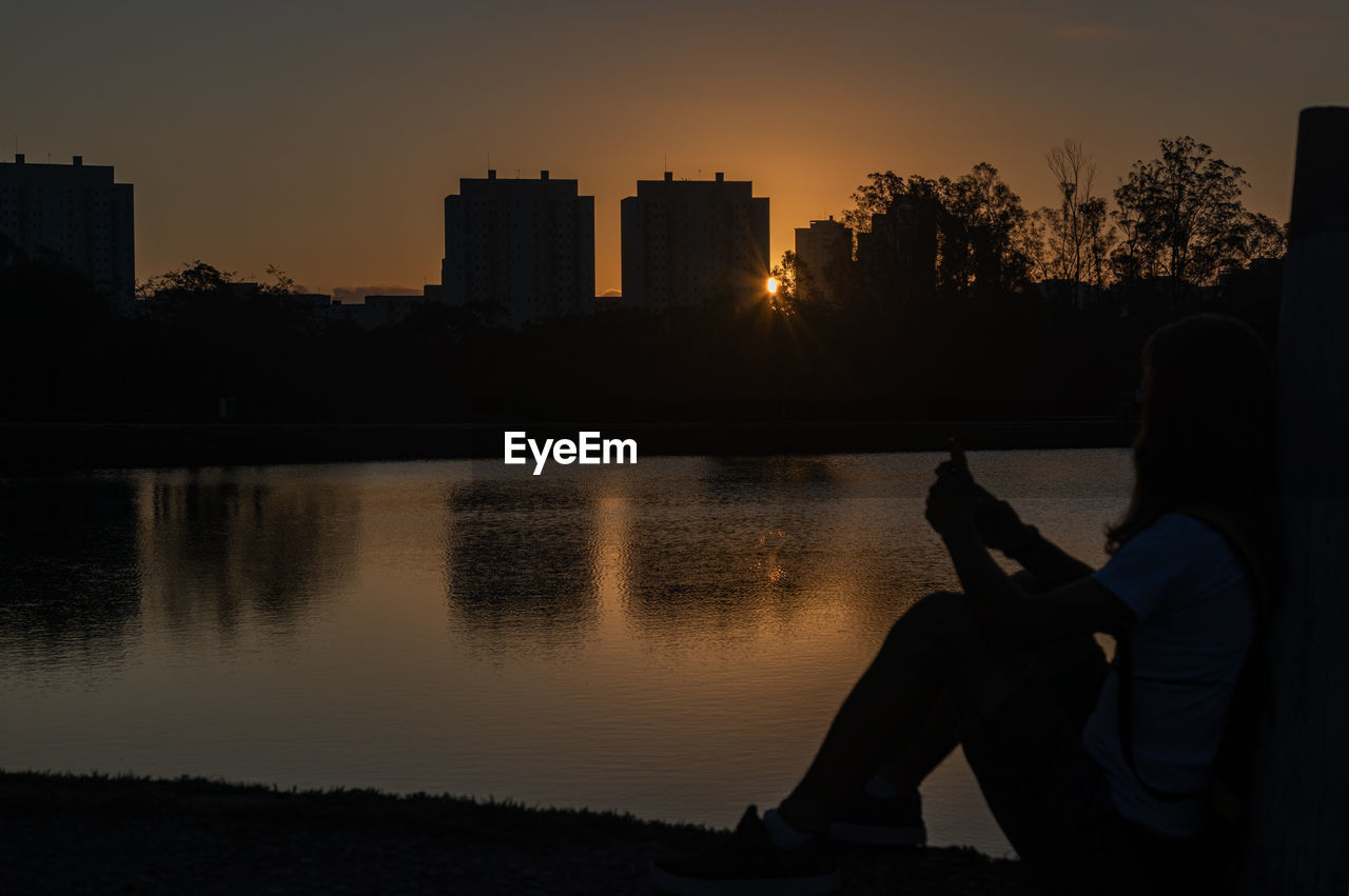 Teenage girl sitting at lakeshore 