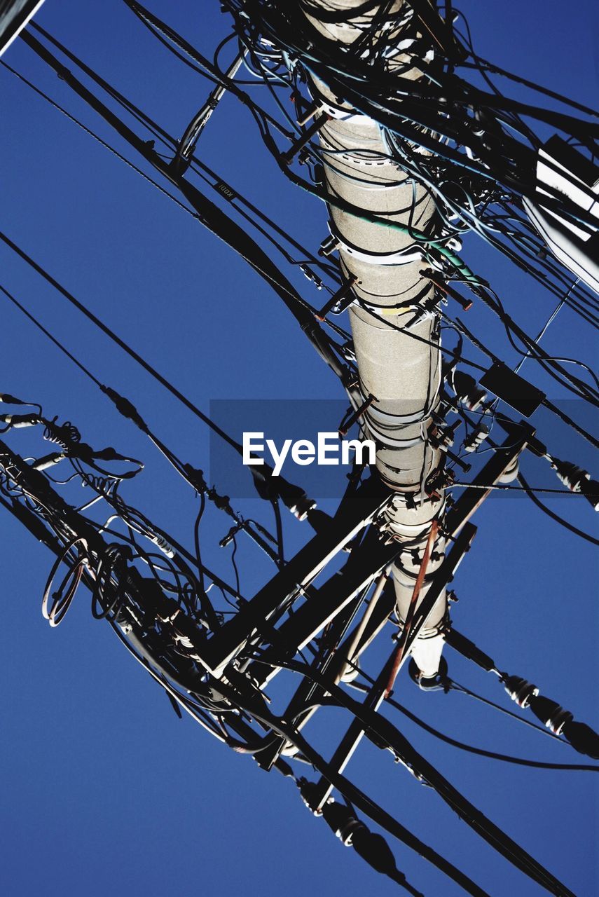 Low angle view of electricity pylon against clear blue sky