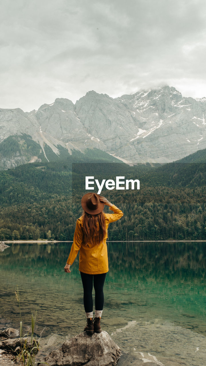 Rear view of woman looking at lake against mountain range