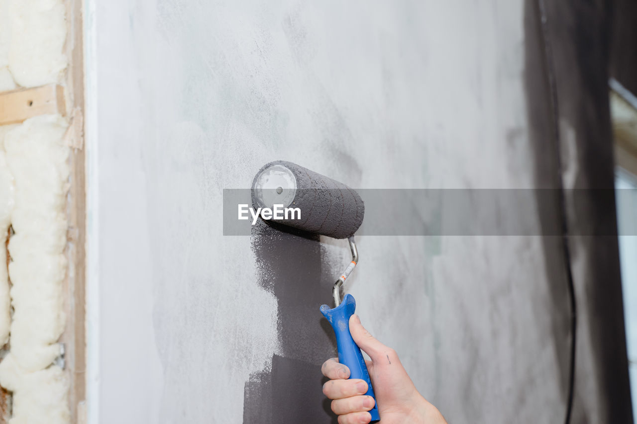 blue, wall, one person, holding, white, hand, wall - building feature, adult, day, lifestyles, architecture, indoors, built structure