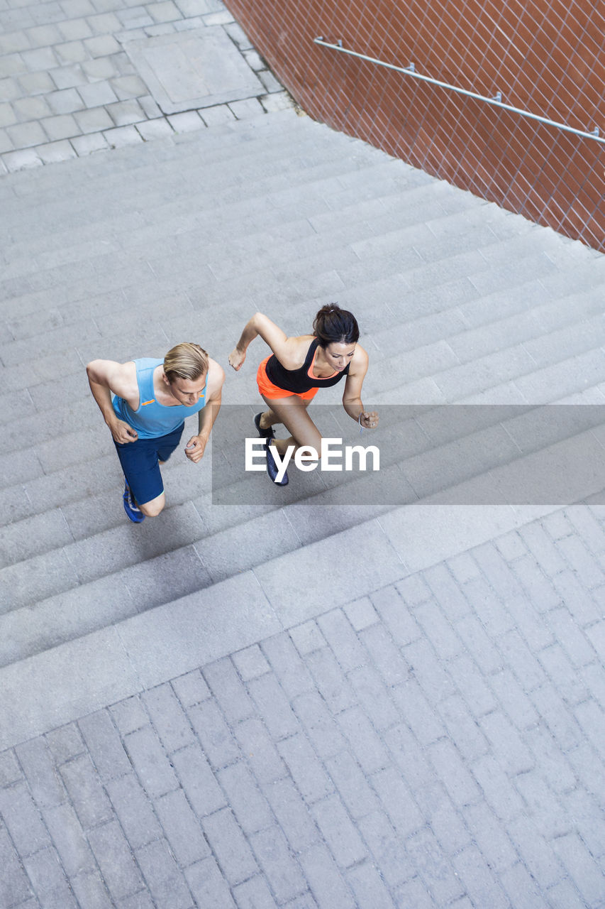 High angle view of fit couple running on steps outdoors