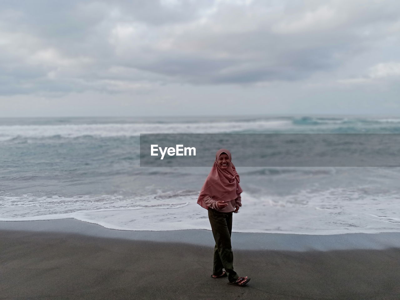 Woman standing on beach against sky