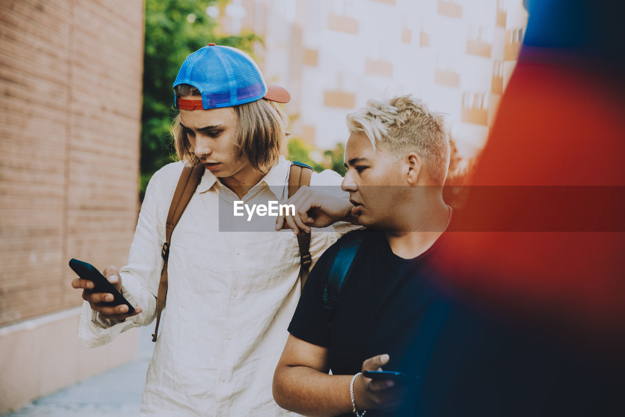 Shocked teenage male friends using smart phone in city