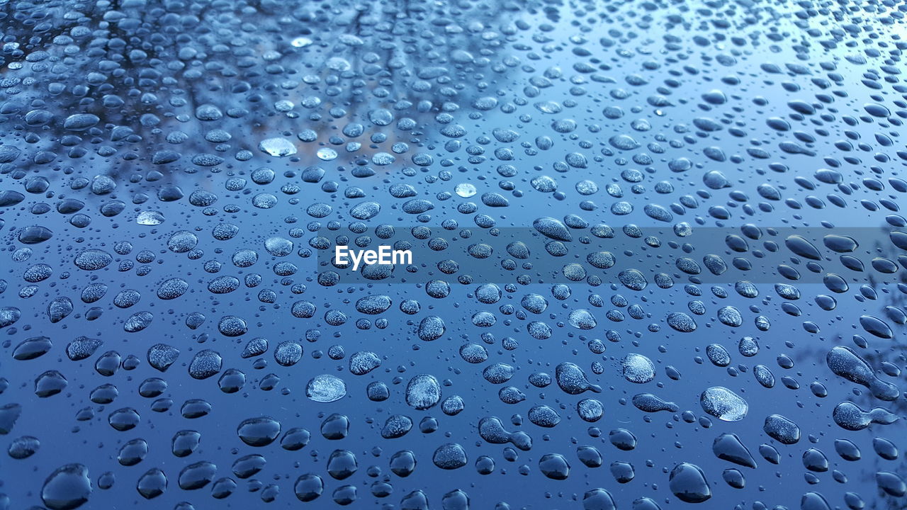 CLOSE-UP OF WET WINDOW AGAINST BLUE SKY