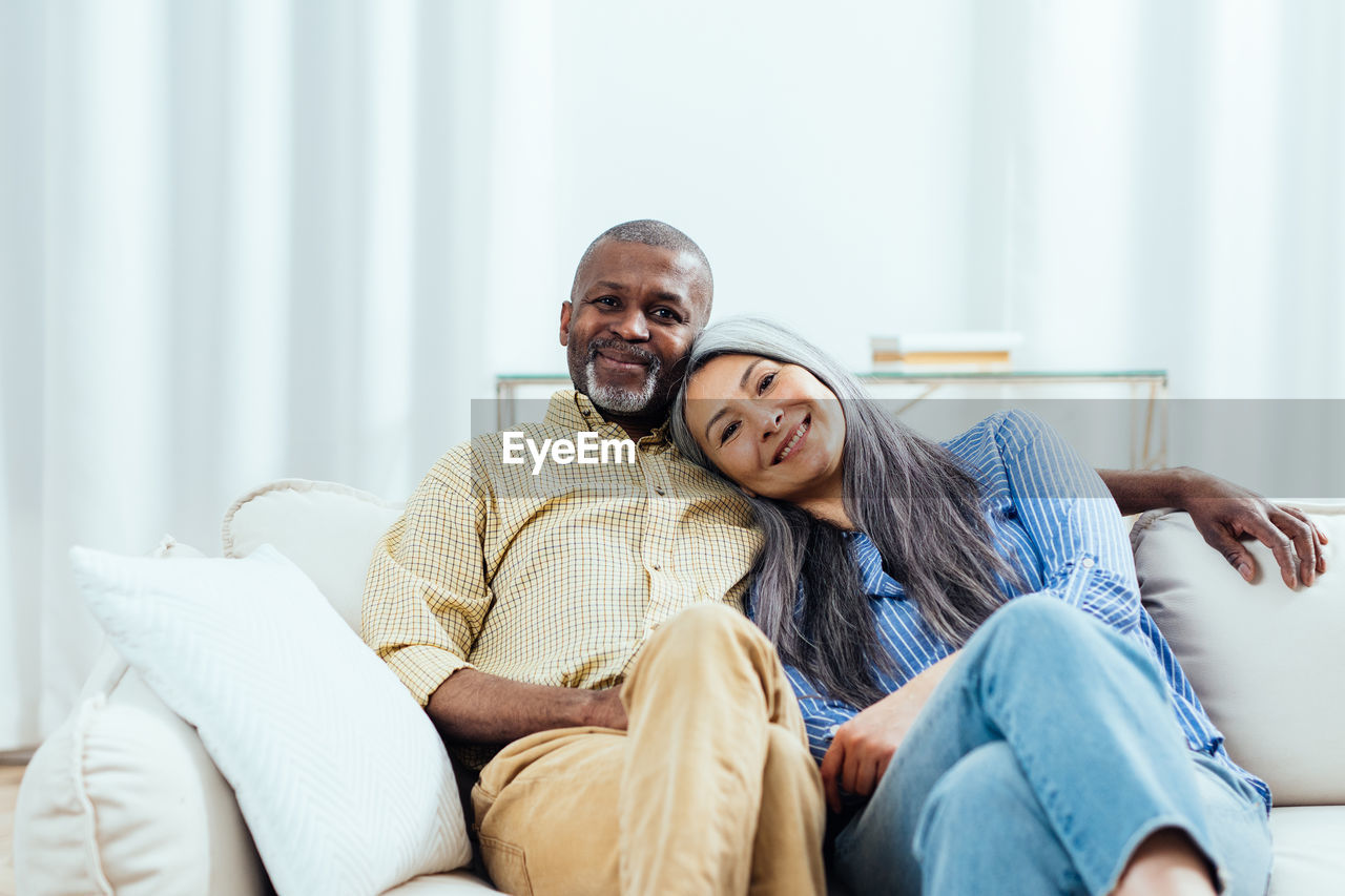 portrait of young woman using mobile phone while lying on bed at home