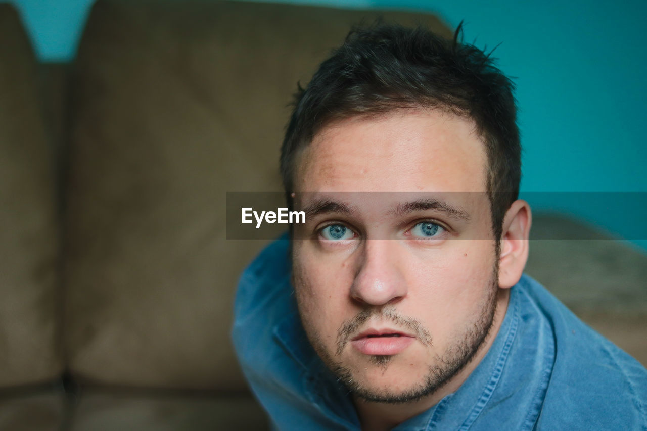 CLOSE-UP PORTRAIT OF YOUNG MAN AGAINST BLUE BACKGROUND