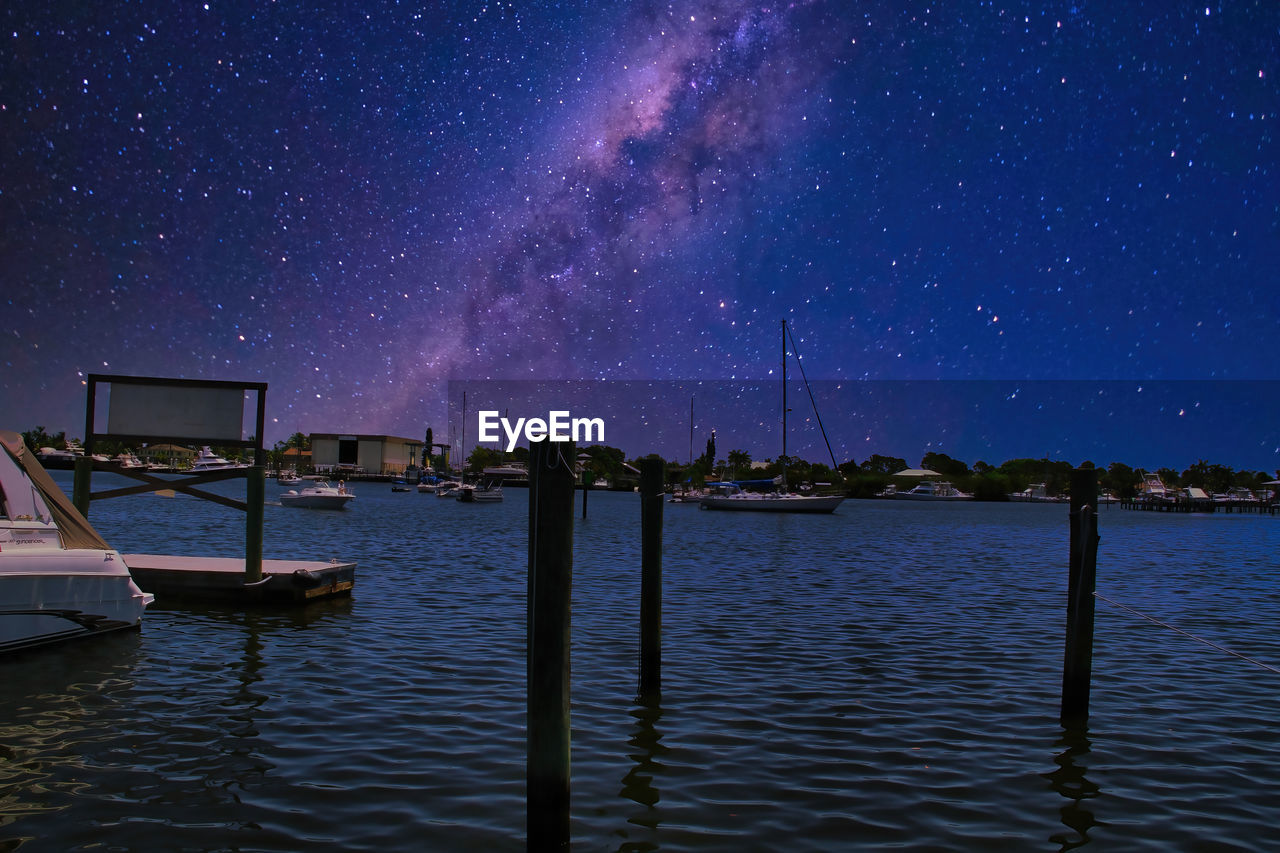 SAILBOATS ON LAKE AGAINST SKY AT NIGHT