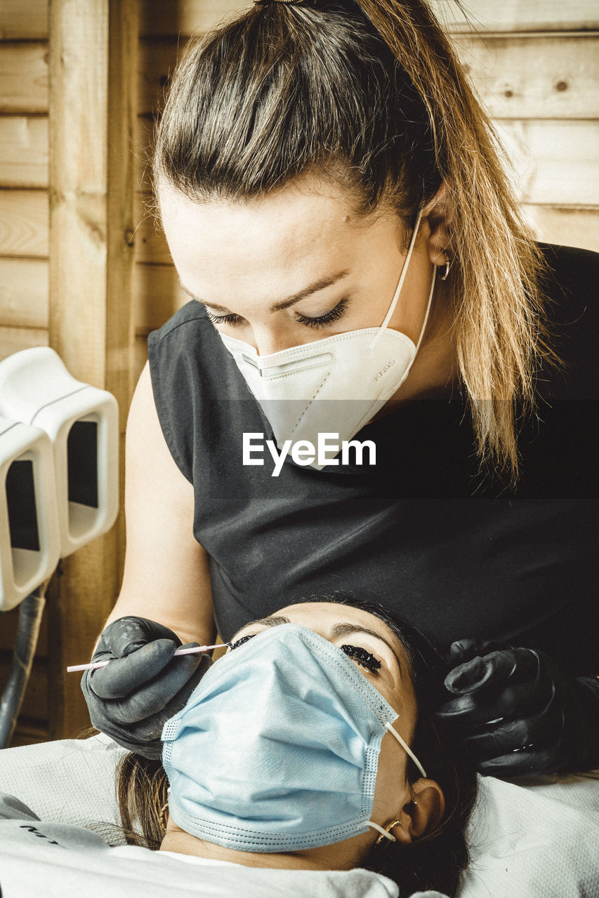 Beautician working with mask and protective screen for the virus covid