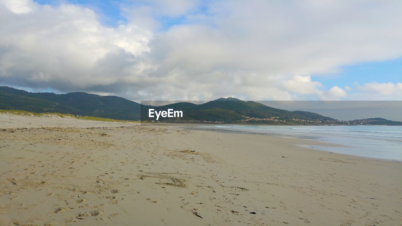 Scenic view of beach against cloudy sky