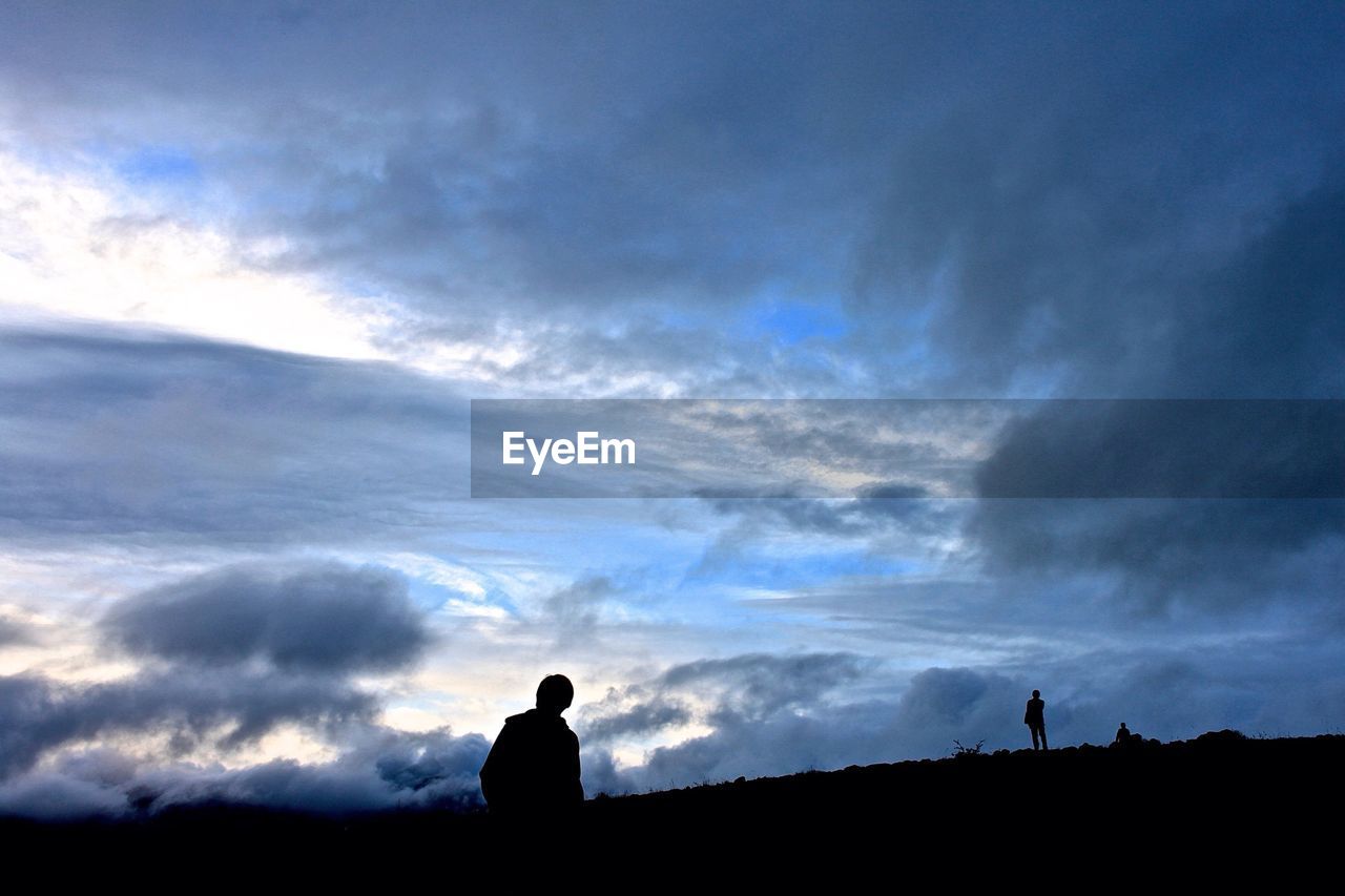 Silhouettes of young men looking at view in mountains