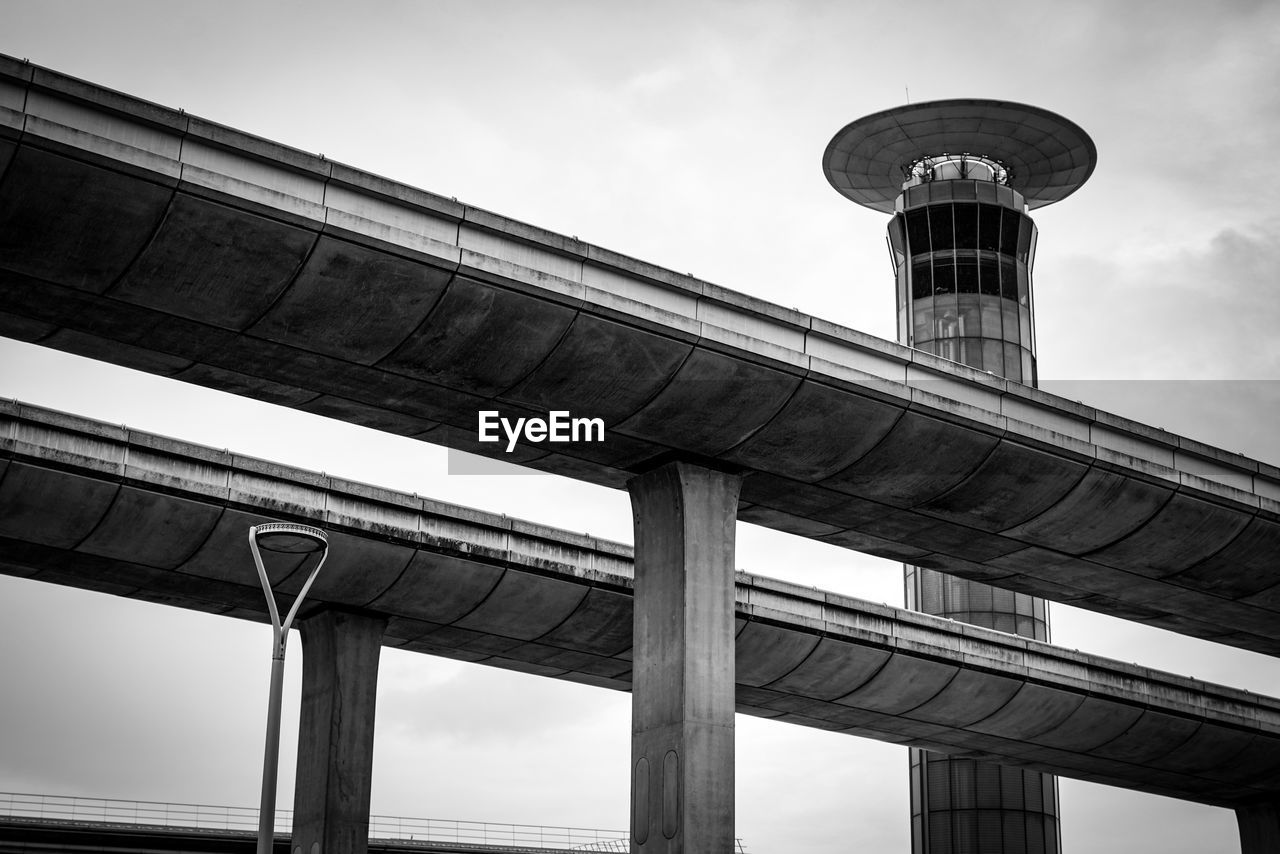 architecture, built structure, black and white, monochrome, sky, bridge, monochrome photography, city, transportation, overpass, low angle view, building exterior, transport, no people, cloud, black, architectural column, nature, white, road, travel, outdoors, travel destinations, public transport, concrete, tower