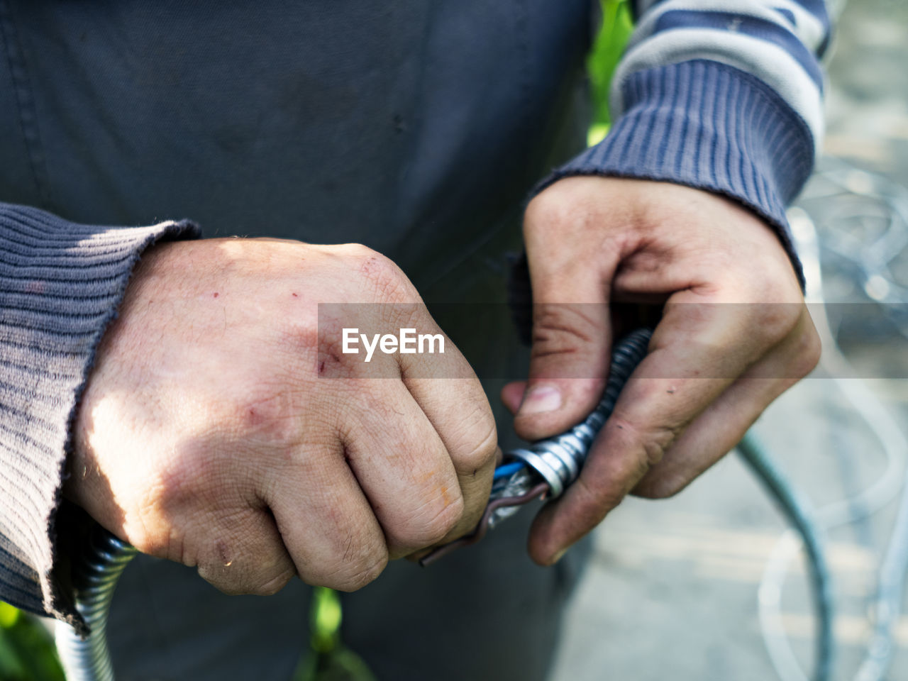 Adult caucasian male pulls cable through metal protective sleeve.