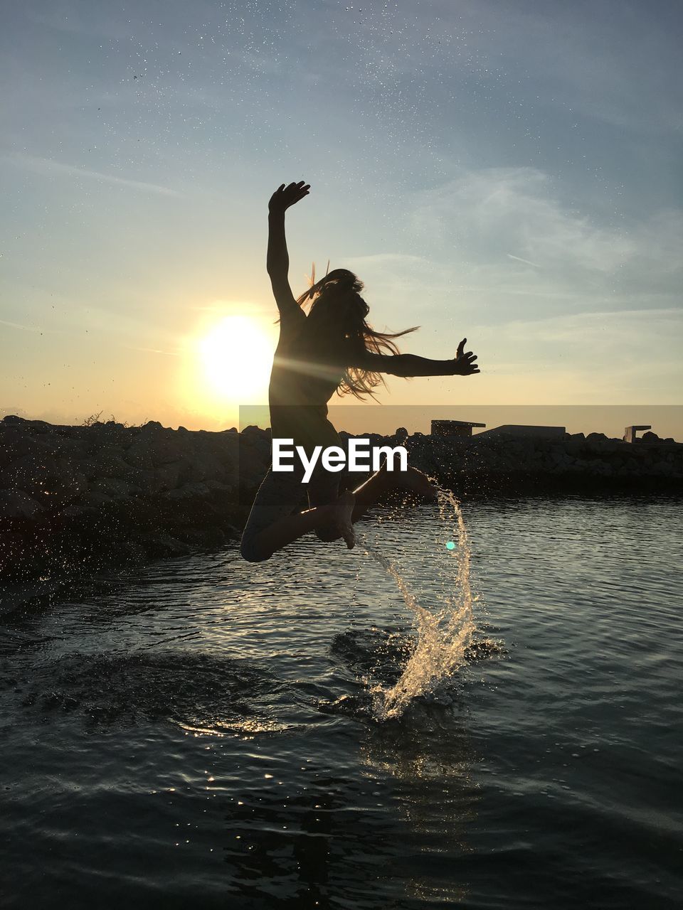 MAN JUMPING IN SEA AGAINST SKY