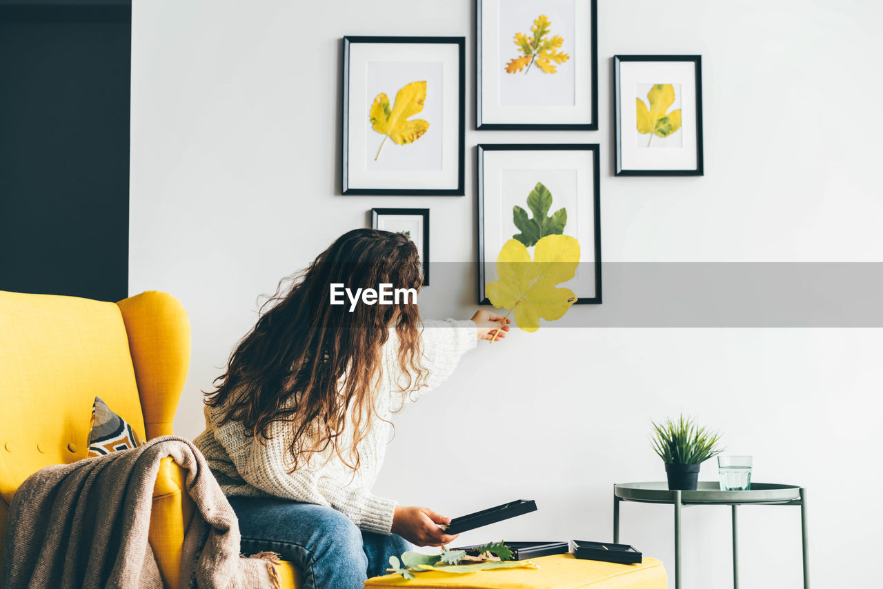 rear view of woman using mobile phone while sitting on table