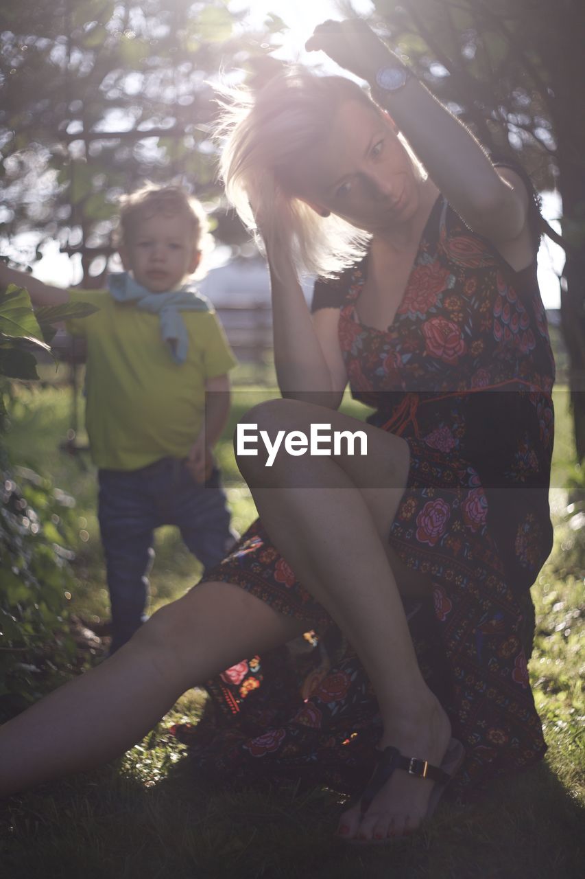 adult, women, sunlight, two people, plant, nature, tree, clothing, female, togetherness, lens flare, back lit, forest, lifestyles, young adult, person, leisure activity, child, emotion, full length, day, men, spring, childhood, casual clothing, photo shoot, outdoors, footwear, sitting, land, human leg, family, fashion, dress, sunbeam, bonding, positive emotion, summer, love, relaxation