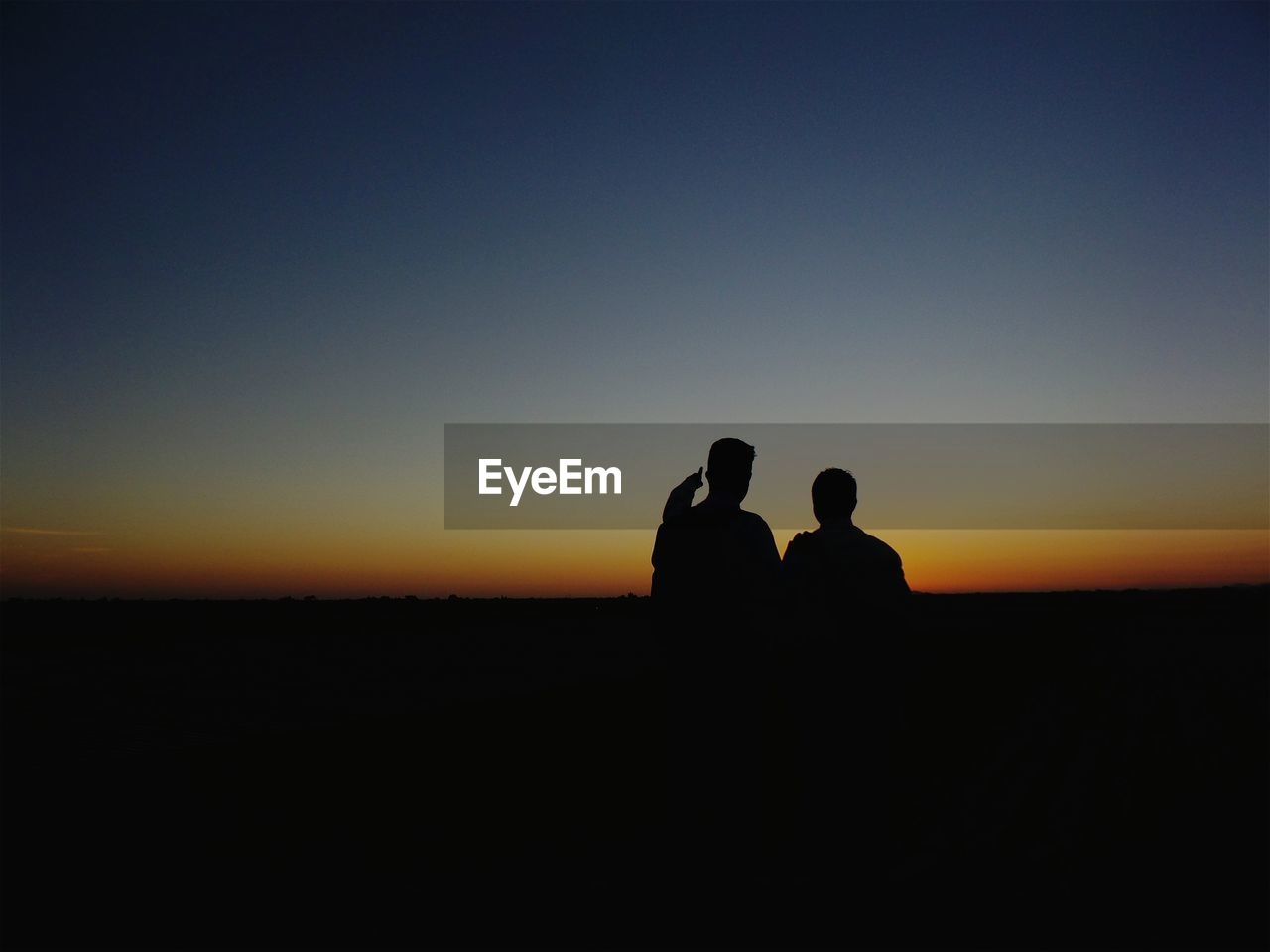Silhouette people on field against clear sky during sunset