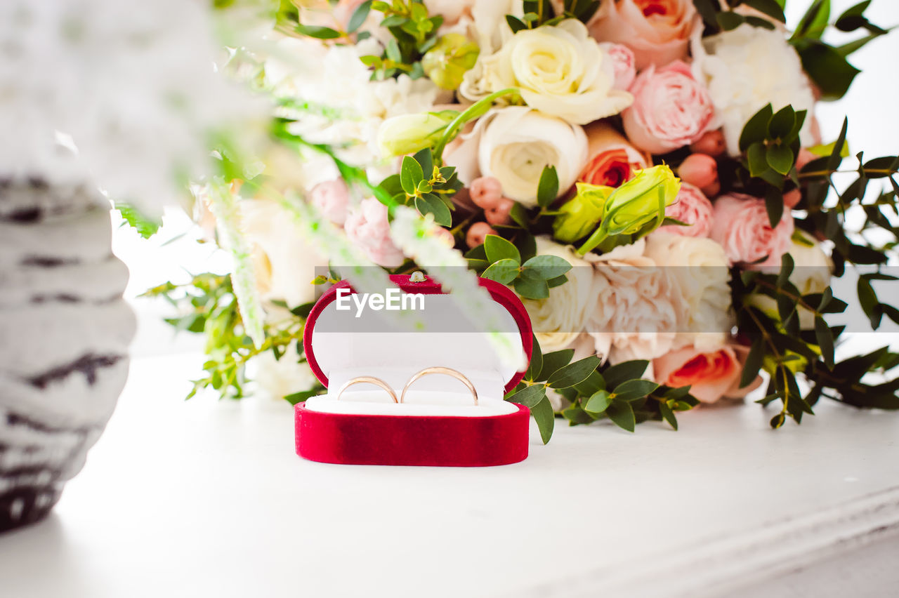 Close-up of wedding rings with bouquet on table