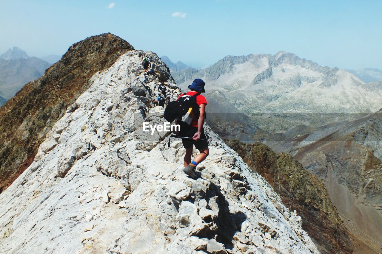 Rear view of men climbing on mountain against sky