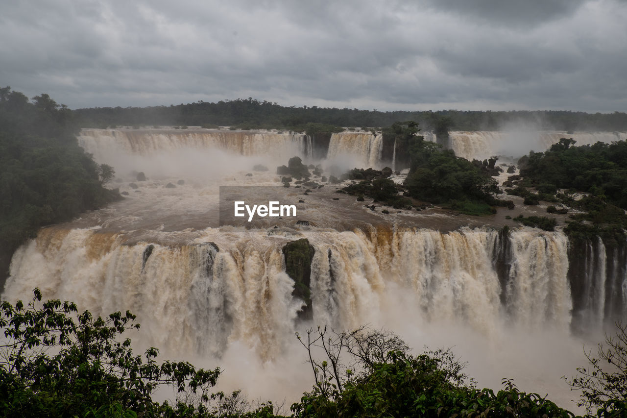 SCENIC VIEW OF WATERFALL AGAINST CLOUDY SKY