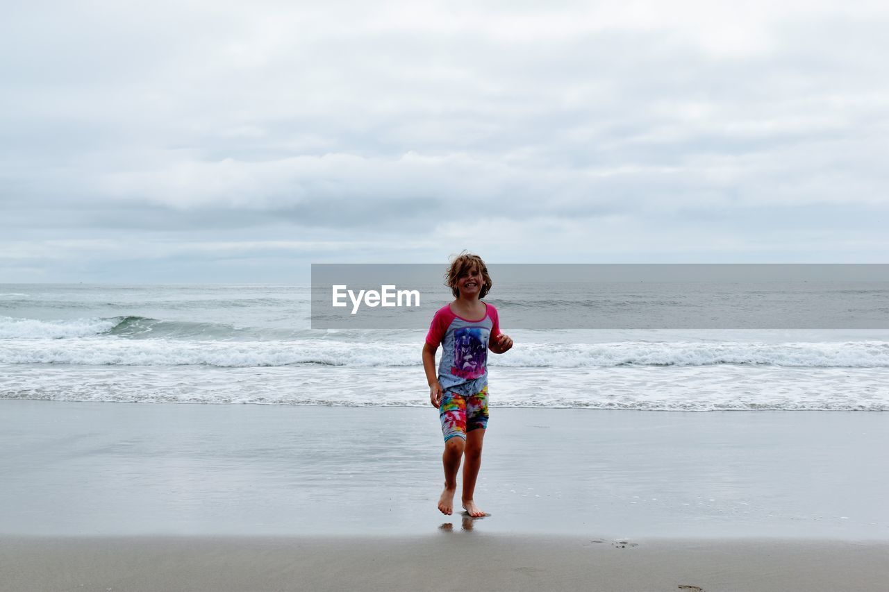 Childn running on beach against sky