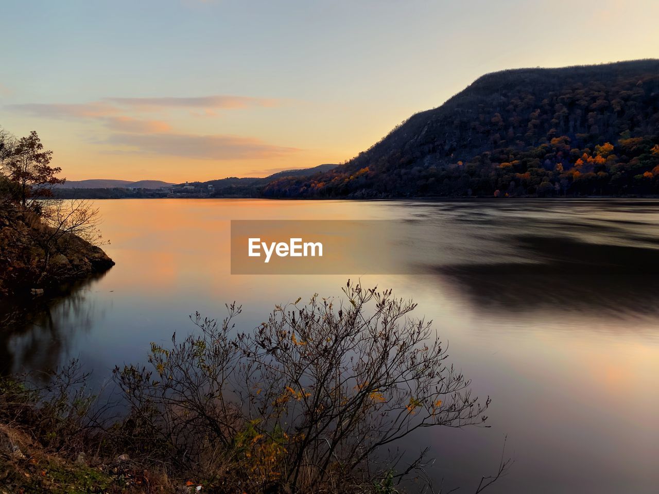 SCENIC VIEW OF LAKE BY MOUNTAINS AGAINST SKY DURING SUNSET