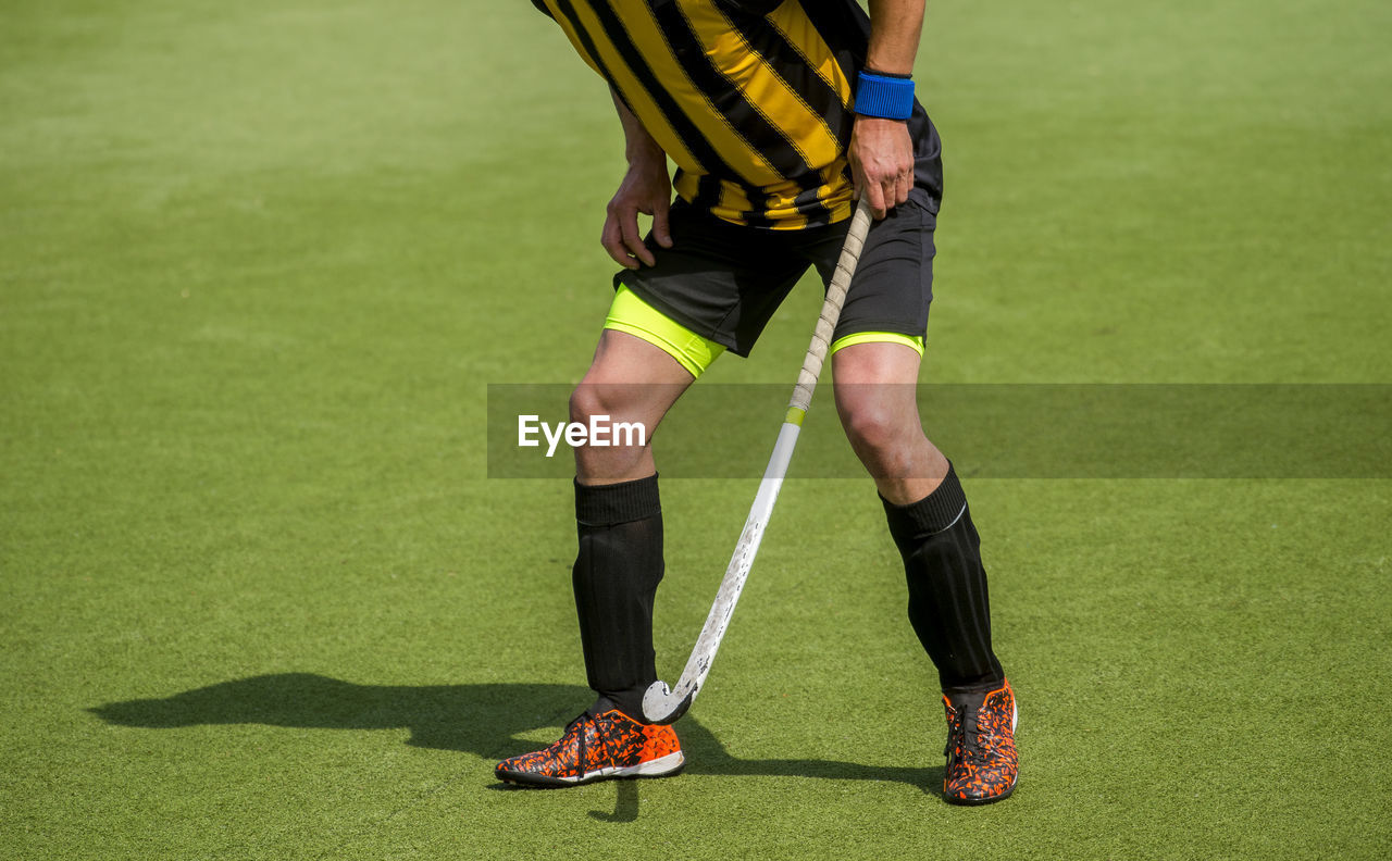 Low section of man playing hockey on grass