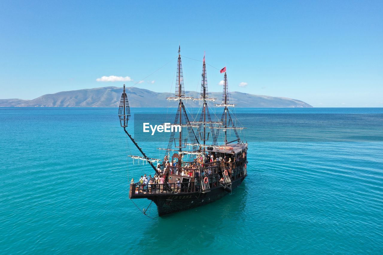 Sailboat in sea against clear blue sky