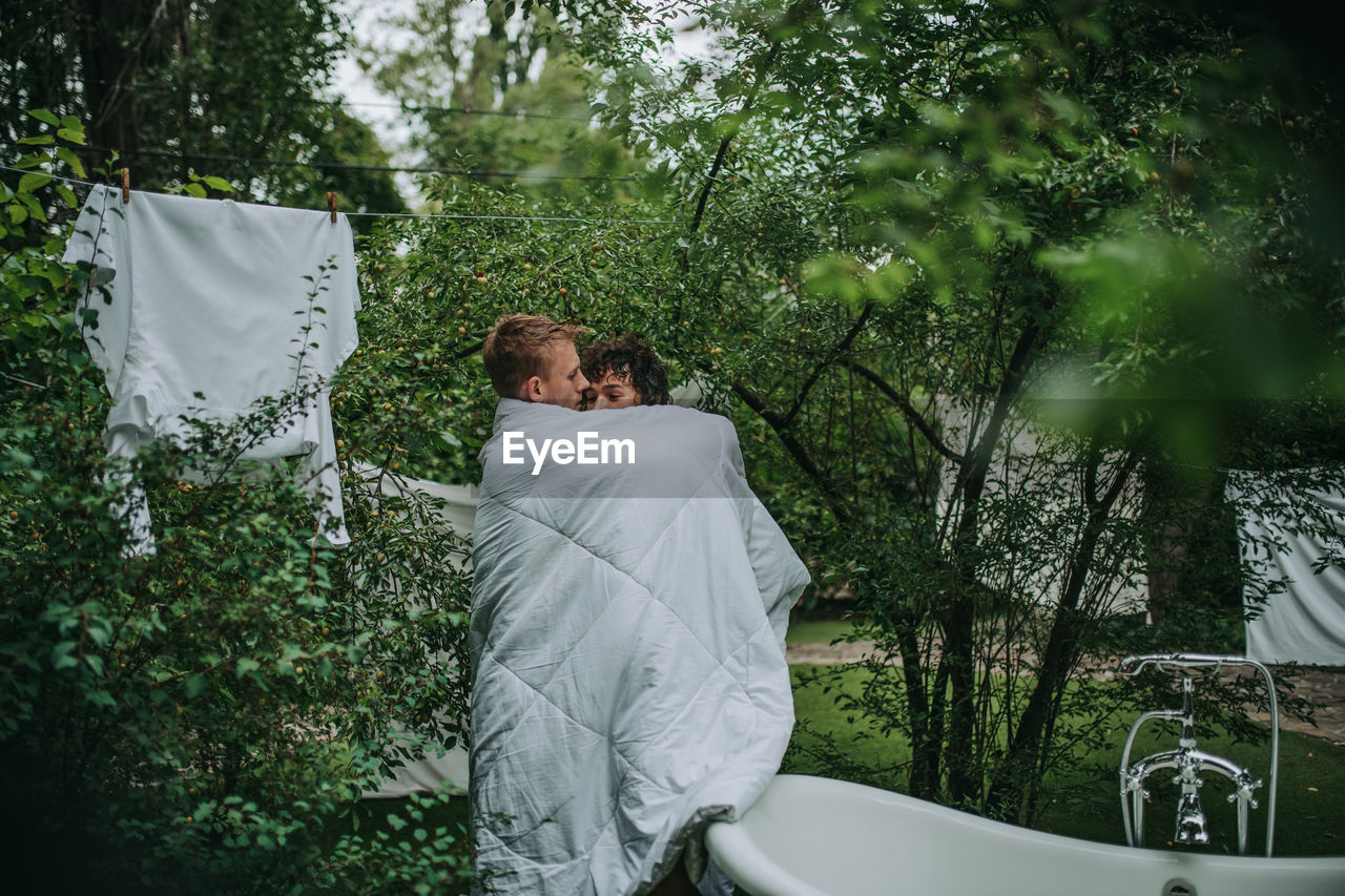 Couple with towel standing against trees