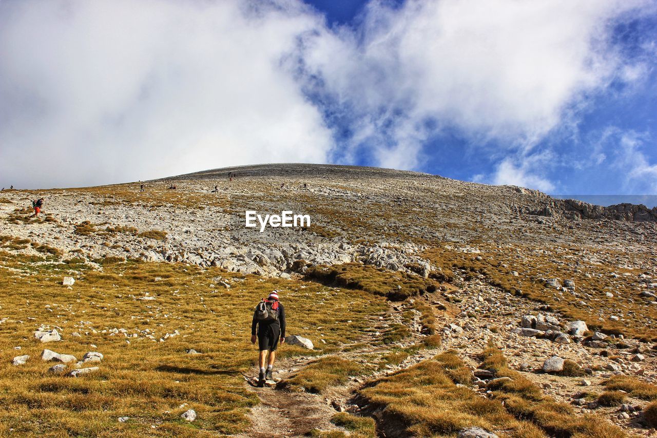 Rear view of man walking on mountain against sky