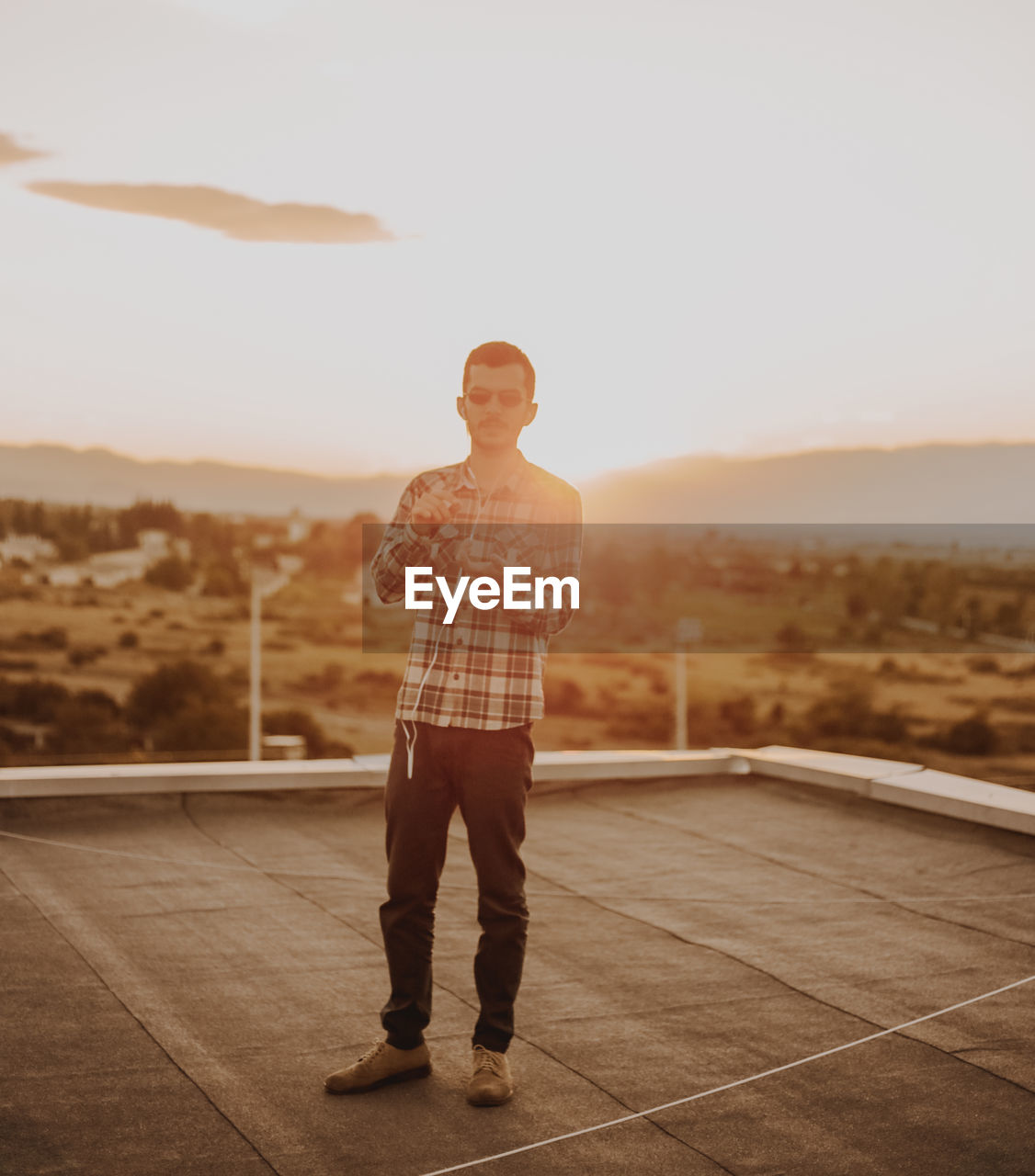 Man standing on terrace against sky during sunset