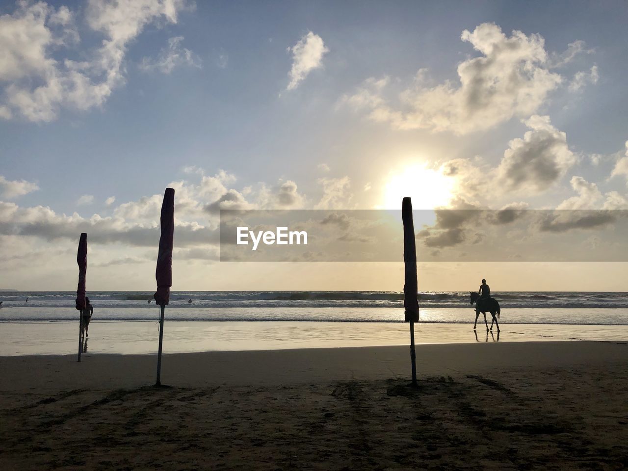 SILHOUETTE WOODEN POSTS ON BEACH AGAINST SKY