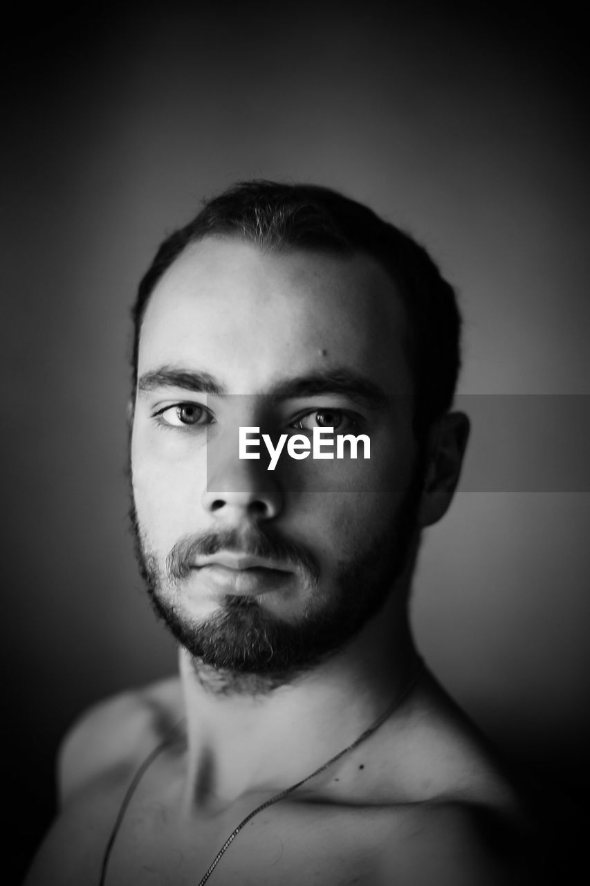 Portrait of shirtless young man against gray background