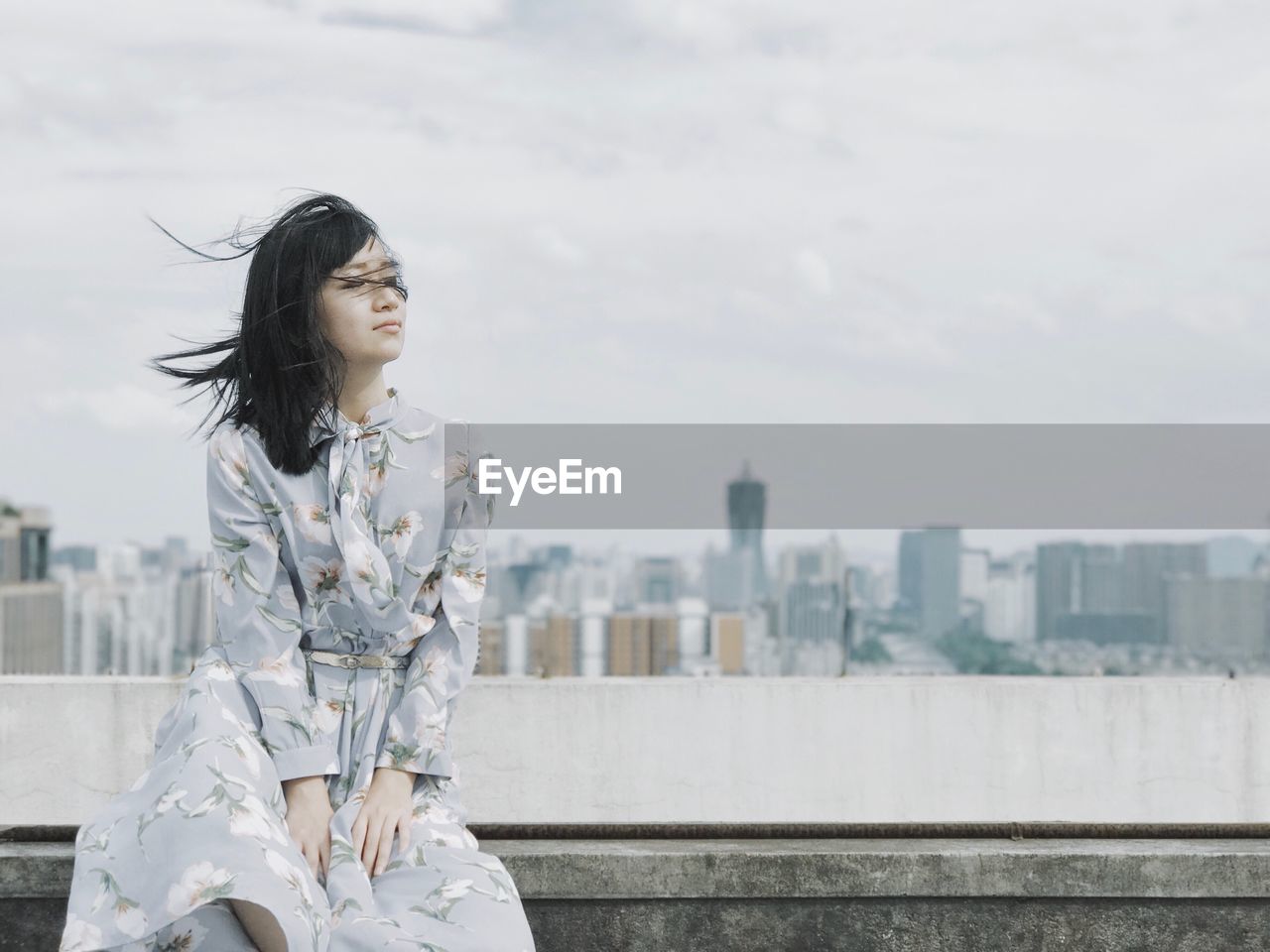 Woman sitting on wall against cityscape