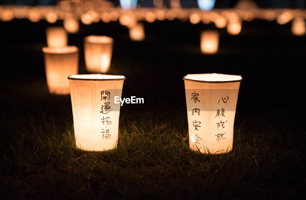 CLOSE-UP OF LIT CANDLES ON WOOD