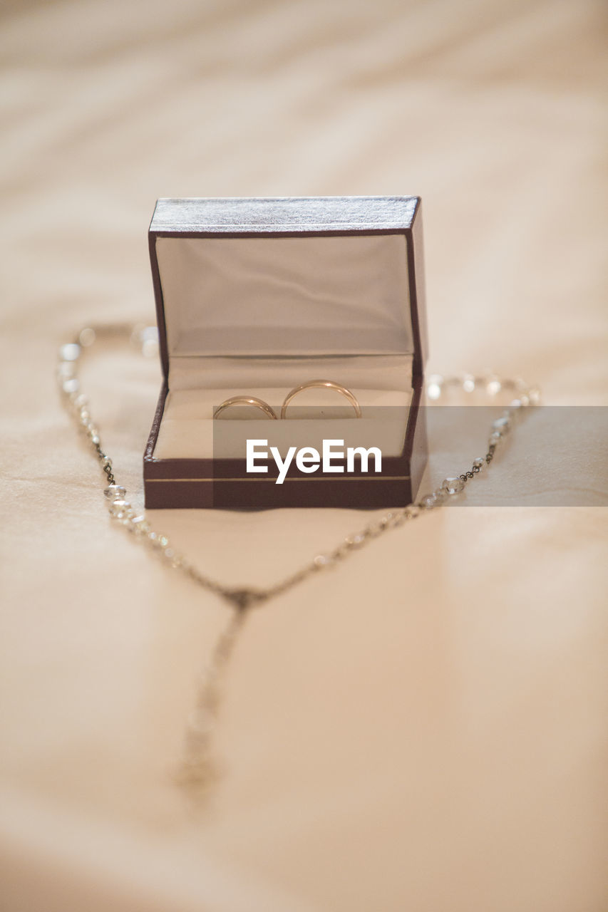 Close-up of wedding rings and necklace