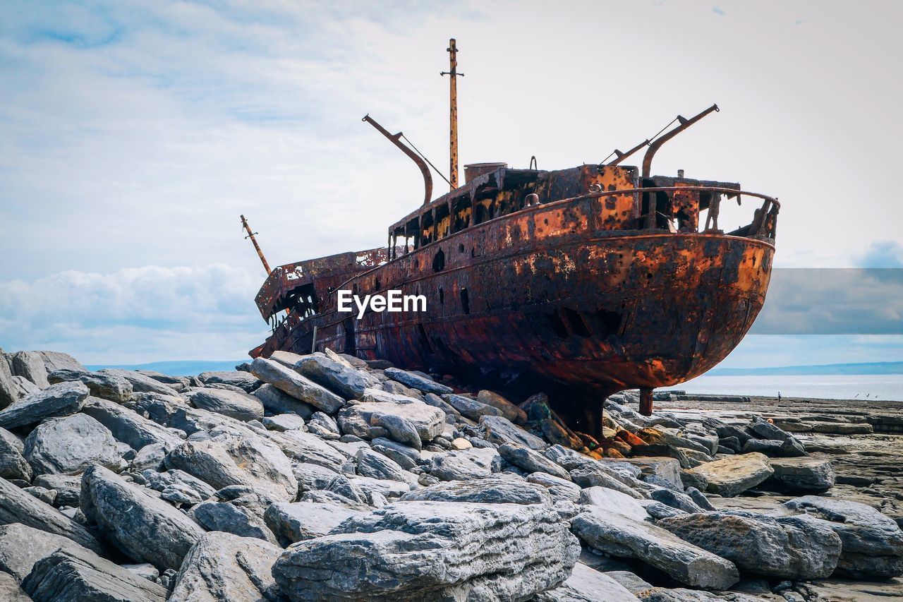 Abandoned ship on shore against sky